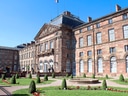 Historisches Gebäude mit gepflegtem Garten und Springbrunnen.