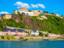 Festung auf Hügel über Flussufer bei klarem Himmel.