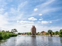Historischer Speicher am Flussufer mit blauem Himmel.