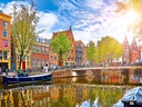 Bunte Häuser und Boote an einem sonnigen Kanal.