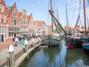 Hafenansicht mit historischen Gebäuden und Segelbooten am Wasser.