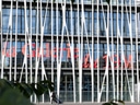 Moderne Glasgebäude mit weissen Säulen und Pflanzen im Vordergrund.