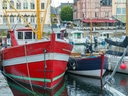 Rote und blaue Boote im Hafen neben einem historischen Gebäude.