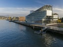 Modernes Gebäude am Flussufer bei sonnigem Wetter.