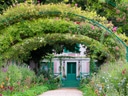 Ein Gartenweg führt zu einem Haus mit Blumenbögen.