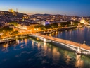 Abendlicher Blick auf beleuchtete Brücke und Fluss in Lyon.