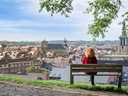 Person auf Bank mit Blick auf Stadtlandschaft und Kirchtürme.