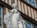 Steinstatue an der Fassade eines Fachwerkgebäudes mit Fenstern.