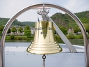 Goldene Schiffsglocke mit Landschaft im Hintergrund.