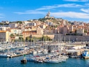Blick auf den Hafen von Marseille mit Booten und Gebäuden im Hintergrund.