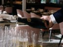 Person füllt Sektgläser in einem eleganten Restaurant.