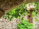 Steinbogen, Blütenranken und Holztür mit Steinwand.