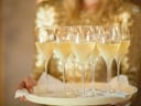 Tablett mit Champagnergläsern in Hand.