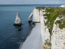 Kreidefelsen von Étretat mit Blumen im Vordergrund.