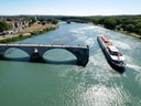 Boot fährt unter historischem Steinbogenbrücke auf Fluss.