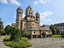 Historisches Gebäude mit Türmen und Eingangstor, Bäume und Himmel im Hintergrund.