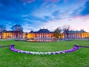 Schloss mit Garten und Blumen im Sonnenuntergang.