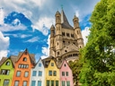 Bunte Häuser und Kirche im Hintergrund unter blauem Himmel.