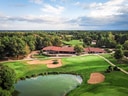 Luftaufnahme eines Golfplatzes mit Clubhaus und Teich.