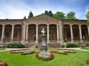 Historisches Gebäude mit Säulen und Garten mit Blumen.