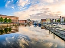 Hafenstadt mit Booten, reflektierender Himmel im Wasser.