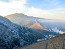 Winterliche Landschaft mit Schloss auf Hügel bei Fluss.