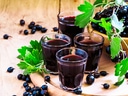 Gläser mit schwarzem Johannisbeersaft und Johannisbeeren auf Tisch.