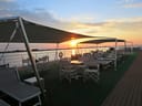 Terrasse eines Schiffes mit leeren Stühlen und Sonnenuntergang über dem Wasser.