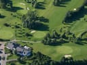 Luftbild eines Golfplatzes mit Clubhaus und Bäumen.
