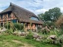 Fachwerkhaus mit Reetdach und Garten.