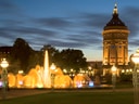 Wasserturm und beleuchteter Springbrunnen bei Nacht.