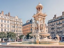 Historischer Brunnen auf einem städtischen Platz mit umliegenden Gebäuden.