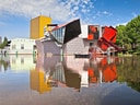 Bunte moderne Gebäude spiegeln sich in einem ruhigen Fluss.