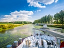 Boot auf einem Fluss mit Bäumen und blauem Himmel.