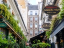 Enges Pariser Café in schmaler Gasse mit Tischen auf dem Gehweg.