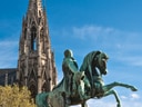 Reiterstatue vor einer Kirche mit hohem Turm.