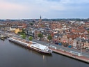 Luftaufnahme eines Flusses mit einem grossen Boot und angrenzendem Stadtviertel.