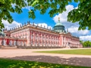 Grosses barockes Gebäude mit Kuppeldach im Park, umgeben von Bäumen.