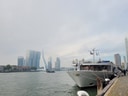 Boot am Fluss mit modernen Gebäuden und Brücke im Hintergrund.