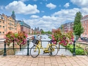 Gelbes Fahrrad auf Brücke vor Kanal und blühenden Blumen in Stadt.