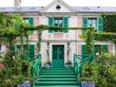Fassade eines Hauses mit grünen Fensterläden und Pflanzen, die die Fassade schmücken.