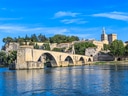 Steinbrücke über Fluss mit historischer Stadt im Hintergrund.