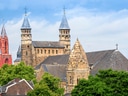 Historische Kirche mit mehreren Türmen vor blauem Himmel.
