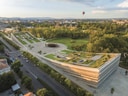 Luftaufnahme eines modernen Gebäudes mit begrüntem Dach und umliegender Parklandschaft.
