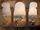 Ausblick durch Bögen auf Stadt und Fluss bei Sonnenuntergang.