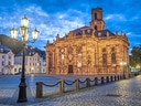 Historische Kirche bei Dämmerung, Saarbrücken mit Kopfsteinpflasterplatz.
