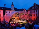 Abendliches Open-Air-Konzert vor einem beleuchteten historischen Gebäude.