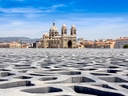 Kathedrale von Marseille hinter geometrischer Dachstruktur.
