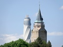 Historischer Turm und moderner Turm vor blauem Himmel.