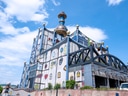 Bunt verzierte Gebäude mit Türmen und geometrischen Formen unter blauem Himmel.